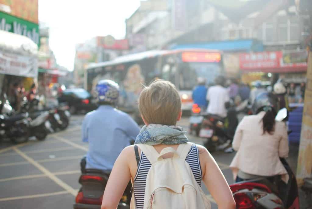 Vita da expat: una persona con zaino osserva una strada affollata e caotica in una città straniera.