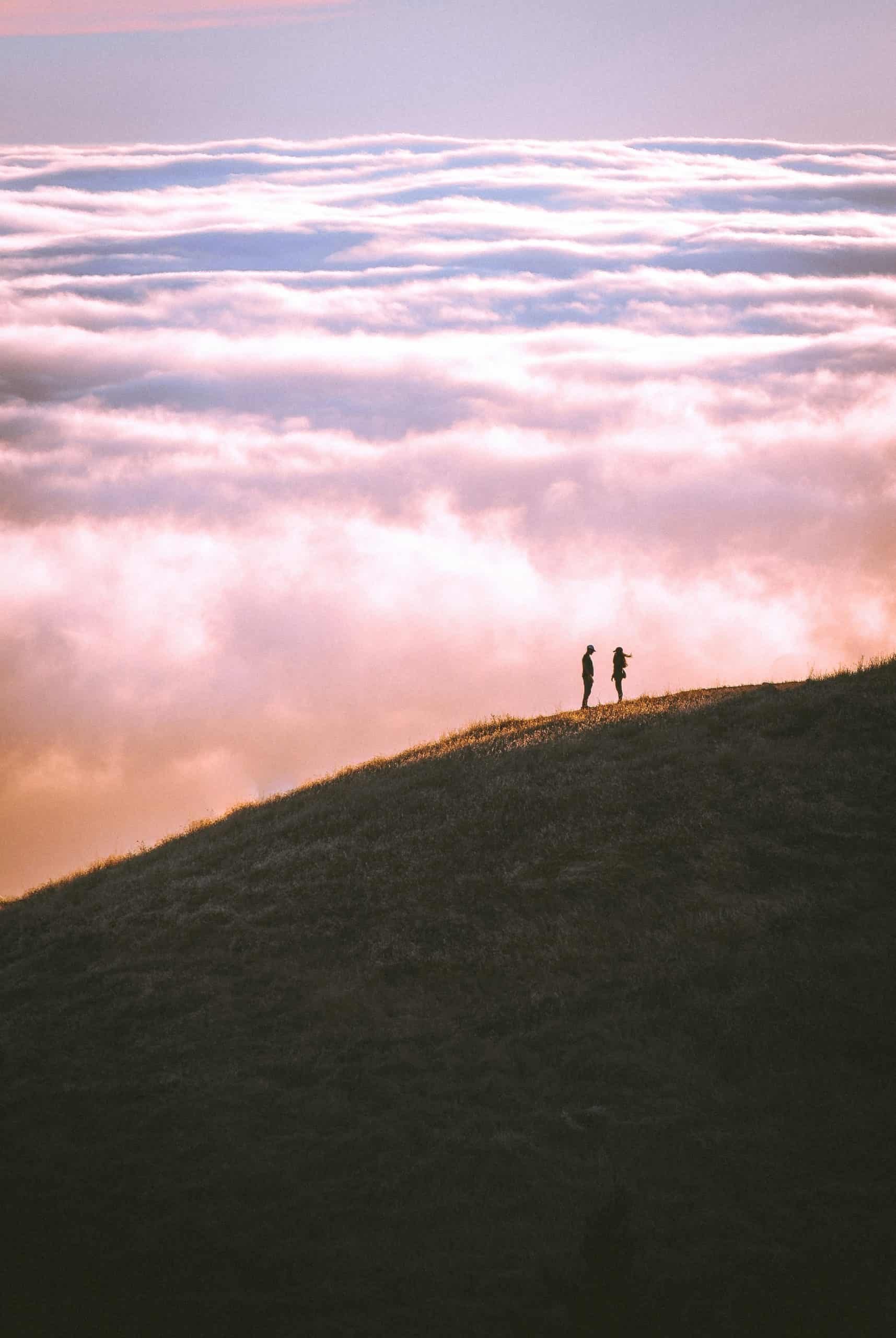 Amore in vetta: Una coppia abbracciata ammira il cielo dalla cima della montagna.